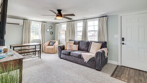 A living room with a grey sofa, a wooden coffee table, a small side table, and a ceiling fan. - 7 Mi to Beach & Ocean! Morehead City Home (Morehead City)