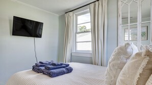 A bedroom with a bed, a TV mounted on the wall, and a window with curtains. - 7 Mi to Beach & Ocean! Morehead City Home (Morehead City)