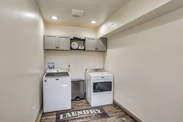 A laundry room with a washing machine, dryer, and a shelf with a Tide detergent box.