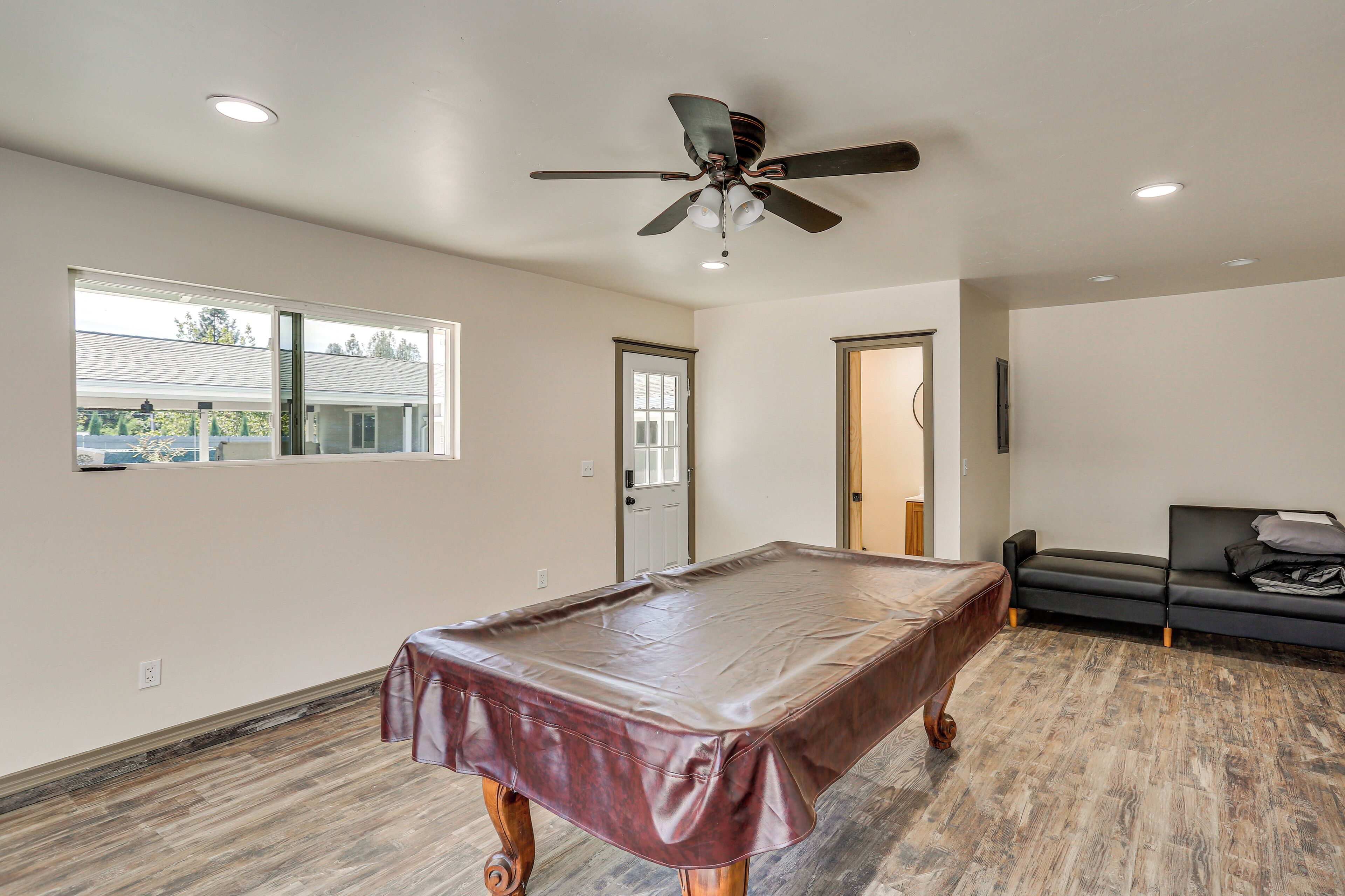 A spacious room with a pool table, a ceiling fan, and a couch.