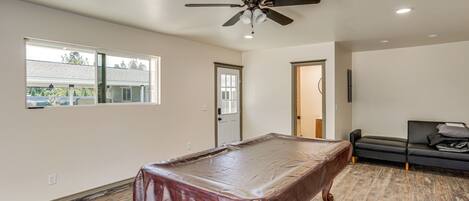 A spacious room with a pool table, a ceiling fan, and a couch.
