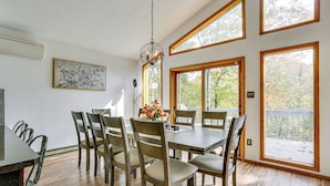 A dining area with a wooden table and chairs, large windows, and a hanging light fixture. - Luxury Home w/ Game Room, 4 Mi to Bushkill Falls! (Bushkill)