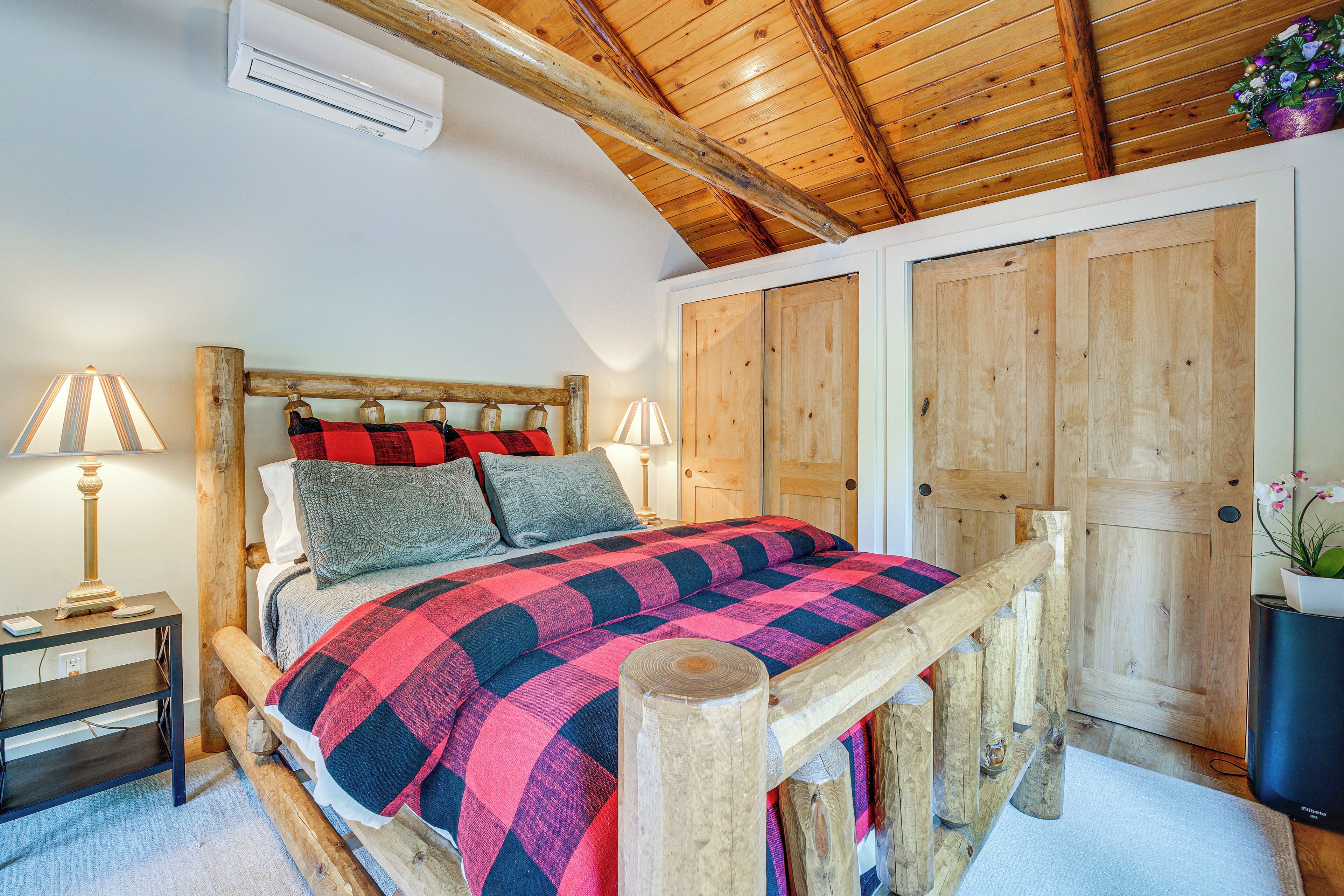 A wooden-framed bed with a checkered blanket, a bedside lamp, and a nightstand.