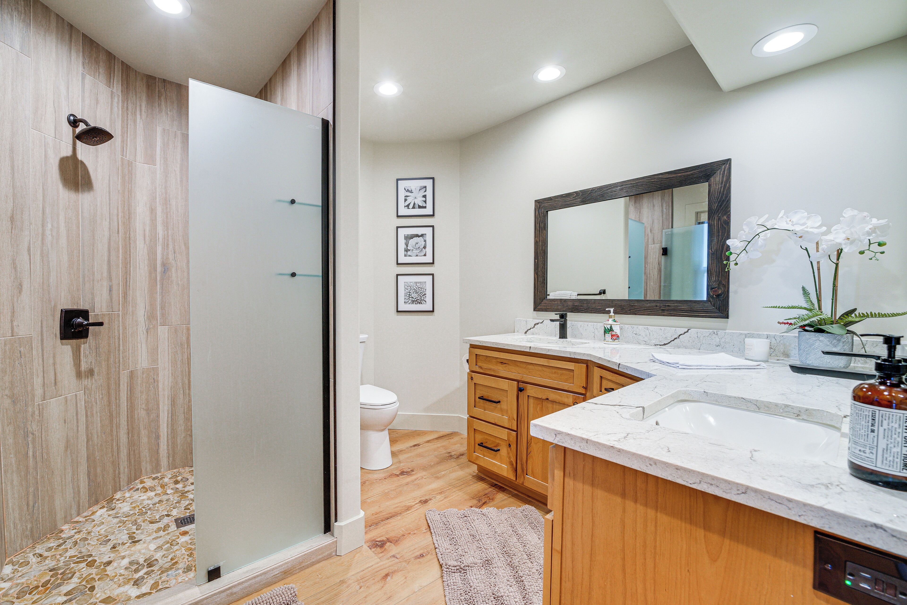 A modern bathroom with a glass shower enclosure, wooden vanity, and a large mirror.