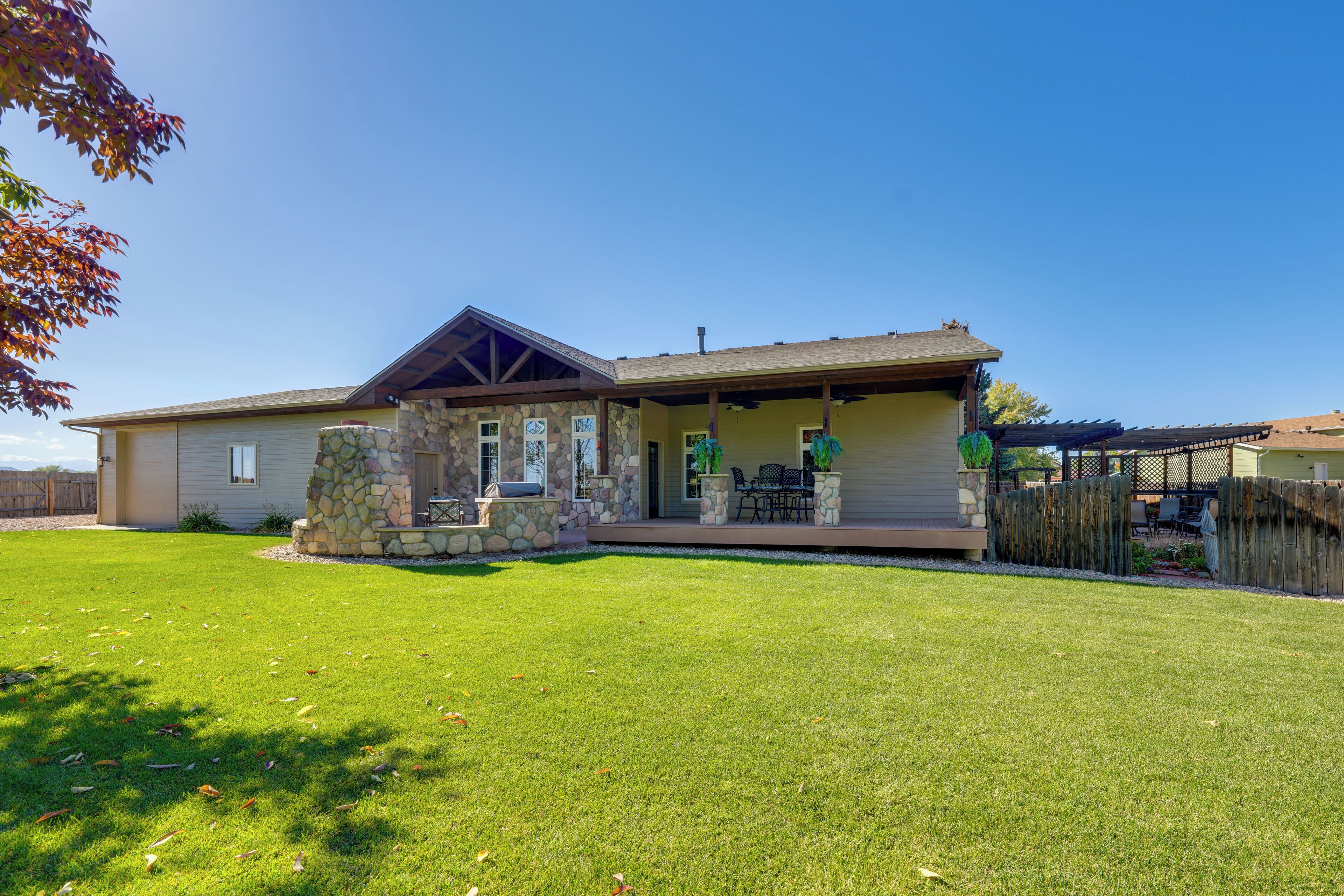 A two-story house with a stone foundation, a covered porch, and a well-maintained lawn.