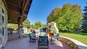 Un patio al aire libre con paredes de piedra, una chimenea de piedra y mobiliario exterior.