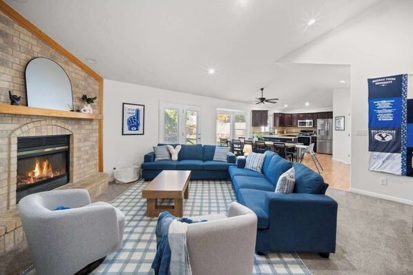 Ein modernes Wohnzimmer mit Kamin, blauem Ecksofa und einem Schachbrettmuster-Teppich.
