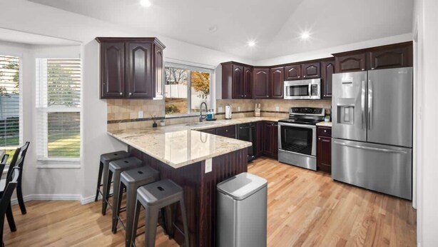 Una cocina moderna con armarios de madera oscura, electrodomésticos de acero inoxidable y una isla grande con taburetes de bar.