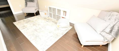 Une pièce avec un canapé gris, un meuble de rangement blanc et un tapis à motifs.