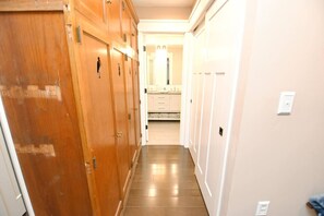A hallway with wooden doors, a tiled floor, and a view into a bathroom with a mirror and sink. - Updated home blocks from ND w/3 full baths (1015) (South Bend)