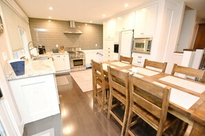 A modern kitchen with white cabinets, a wooden dining table, and stainless steel appliances. - Updated home blocks from ND w/3 full baths (1015) (South Bend)