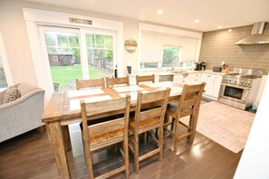 Una cocina moderna con comedor, ventanas amplias y vista al jardín trasero.