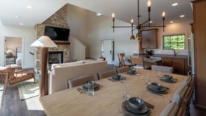 Una cucina moderna con camino in pietra, pensili in legno e zona pranzo per sei persone.