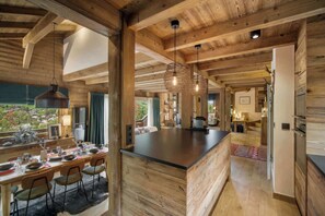 Una cocina amplia con una isla grande, vigas de madera e iluminación colgante.