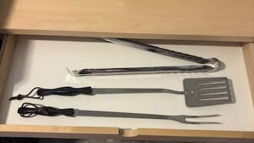 A drawer with kitchen utensils including a spatula, tongs, and a pair of scissors.