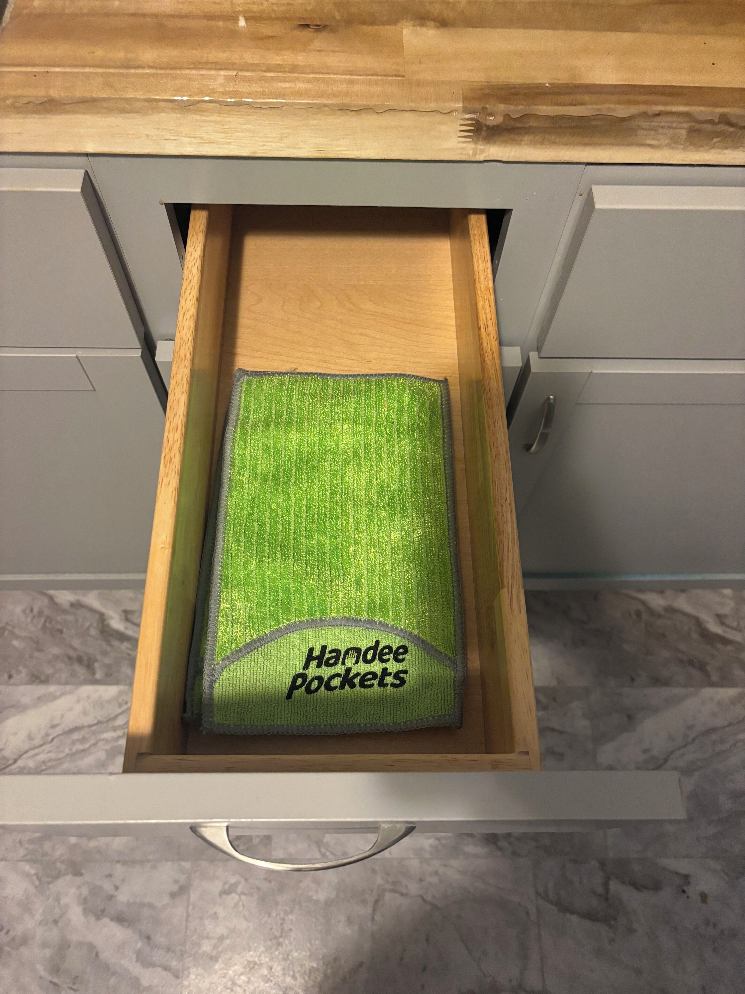 A drawer with a green fabric labeled "Handee Pockets" inside.