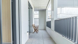 A narrow corridor with a wooden door, a chair, and a metal railing. - Stylish 1BR & 1LR Apartment | Cozy City View (Bratislava)