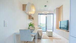 A modern living room with a dining area, a TV, and a large window. - Stylish 1BR & 1LR Apartment | Cozy City View (Bratislava)