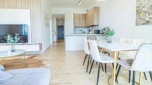 Una sala de estar moderna con un sofá, una mesa de comedor con sillas, una zona de cocina y un televisor.