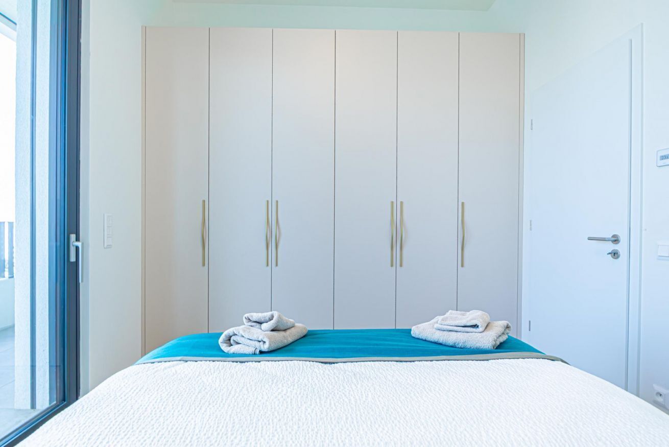 A bedroom with a bed, a blue mattress, a white quilt, and a wardrobe with three doors.