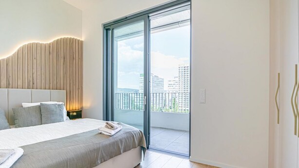 Un dormitorio con cama, mesita de noche y vistas a un balcón.