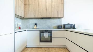Une cuisine avec des armoires blanches, un plan de travail en bois, un four à micro-ondes et un four traditionnel.