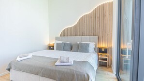 Un dormitorio moderno con una cama grande, lámparas de noche y una pared de acento de madera.