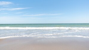 Een strand met heldere lucht en rustige golven.