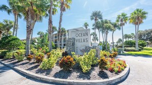Bordje voor Ocean Villas, met een stenen basis en een heldere lucht op de achtergrond.