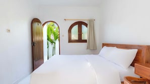 A bedroom with a wooden bed, a small window with a curtain, and a door with a plant outside. - Casa Feliz Guest House (Bangli)