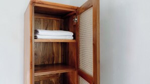 A wooden cabinet with a woven door, containing folded white towels. - Casa Feliz Guest House (Bangli)