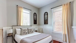 Un dormitorio con una cama grande, dos mesitas de noche y una ventana con cortinas.