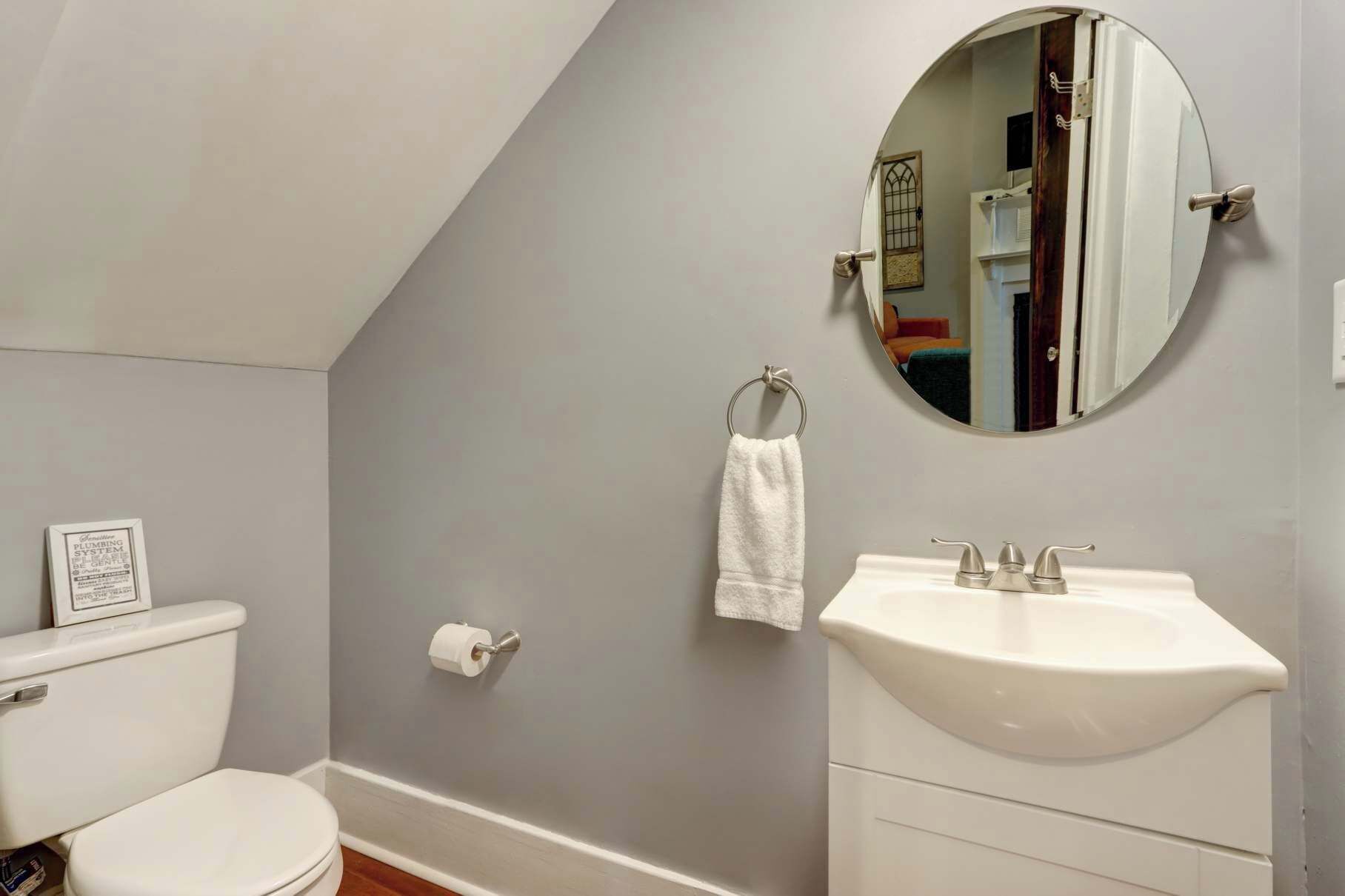 A bathroom with a toilet, a sink, a towel rack, and a mirror.