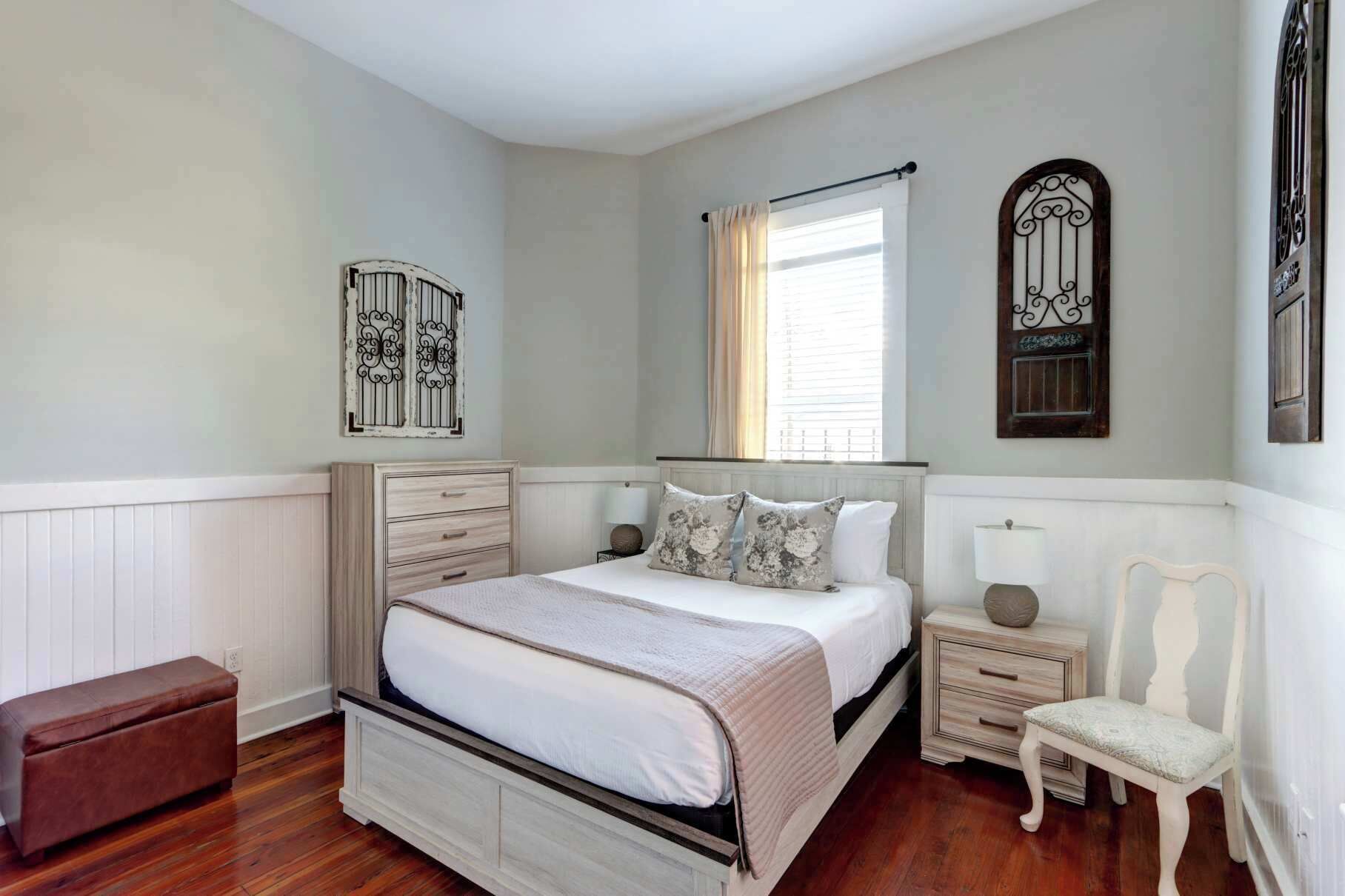 Une chambre à coucher comprenant un lit, des tables de chevet, un banc et des éléments décoratifs muraux.