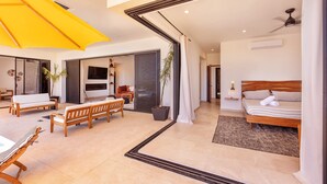 A modern hotel room with a bed, a sofa, a dining table, and a large window. - Villa Damiana by The Agency Baja (El Pescadero)