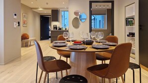 A modern dining area with a round table set for six, surrounded by six brown chairs. - Brand New & High-End, 3 Bedrooms 2 Bathrooms, Central Apartment (Bergen)