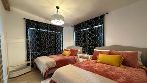 A bedroom with two beds, a nightstand, a lamp, and a hanging light fixture. - Private duplex (second floor) centrally located to beaches and the city of Miami. (Miami)