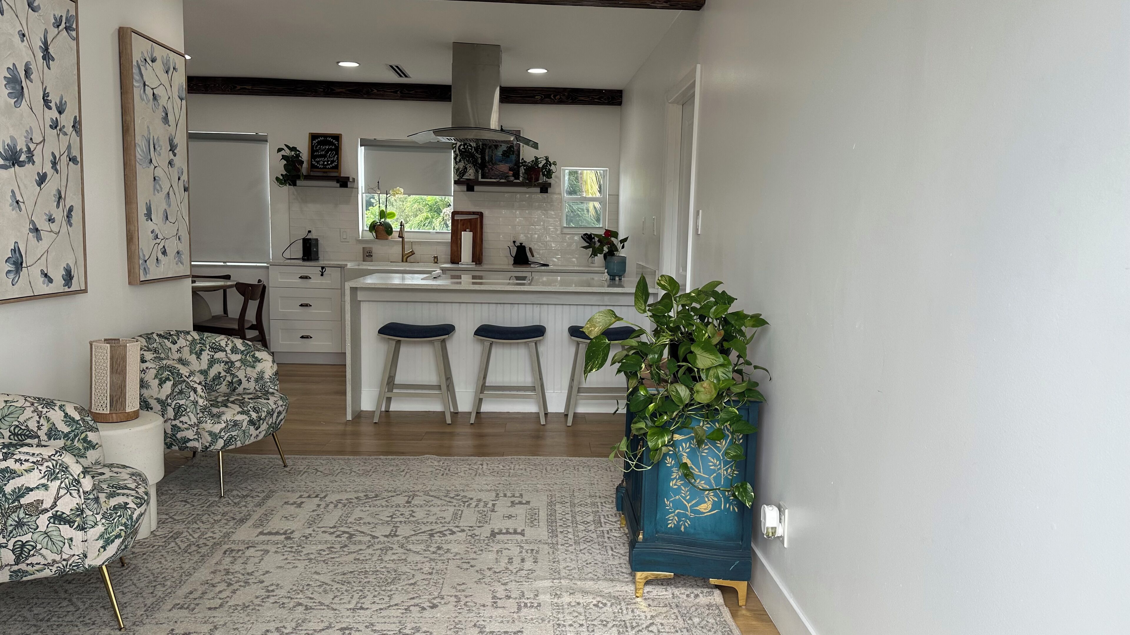 Une cuisine moderne avec des meubles blancs, un îlot central doté de tabourets et un mur d’accent bleu.
