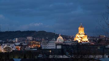 Un paisaje urbano al anochecer con edificios iluminados, incluyendo una iglesia destacada con una cúpula y un edificio gubernamental con una bandera.