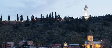Un pueblo con una estatua destacada en una colina, una iglesia con un campanario y varios edificios en la base.