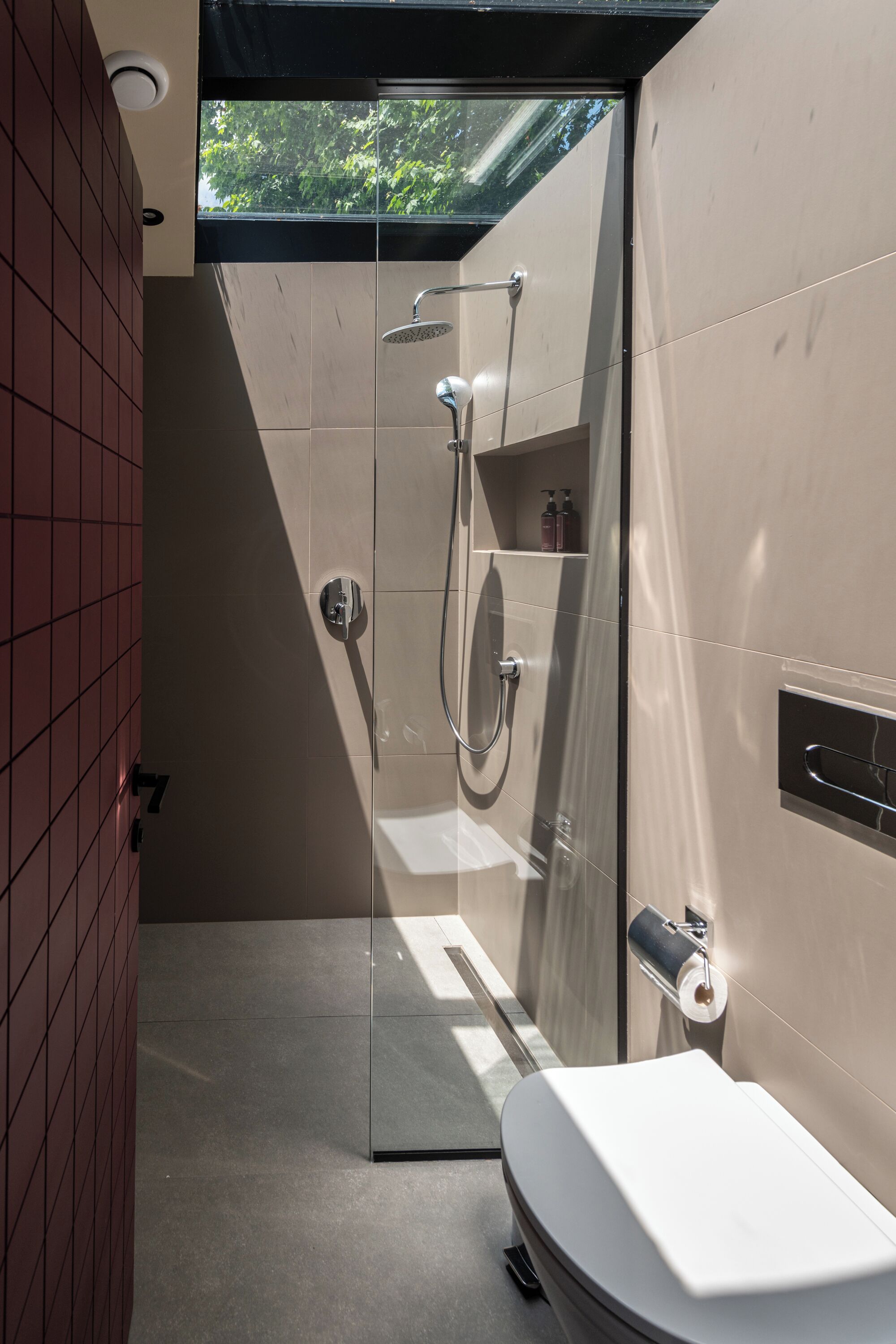 A modern bathroom with a glass shower enclosure, a toilet, and a towel rack.