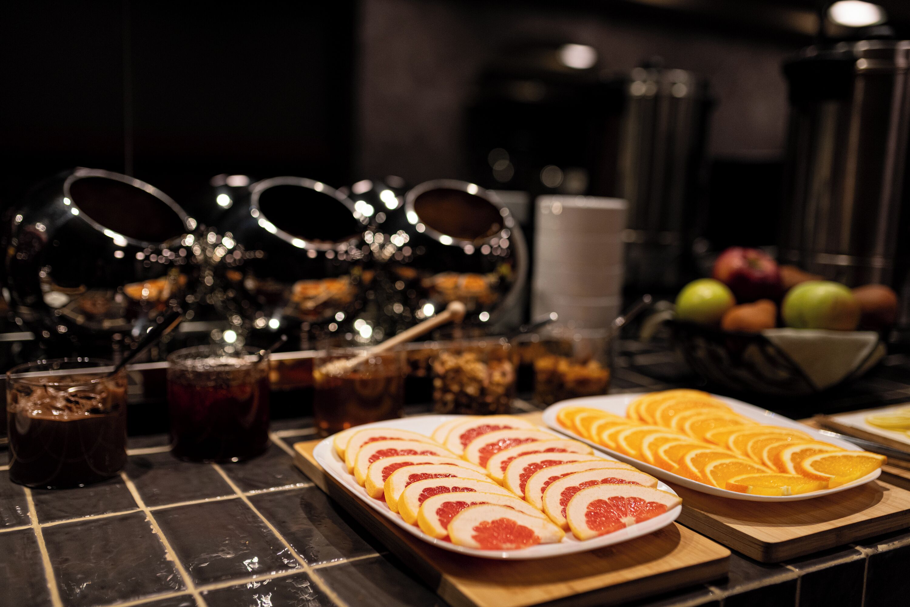 Une table de buffet avec des fruits coupés en tranches, des boissons et des condiments.