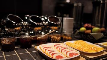 Une table de buffet avec des fruits coupés en tranches, des boissons et des condiments.