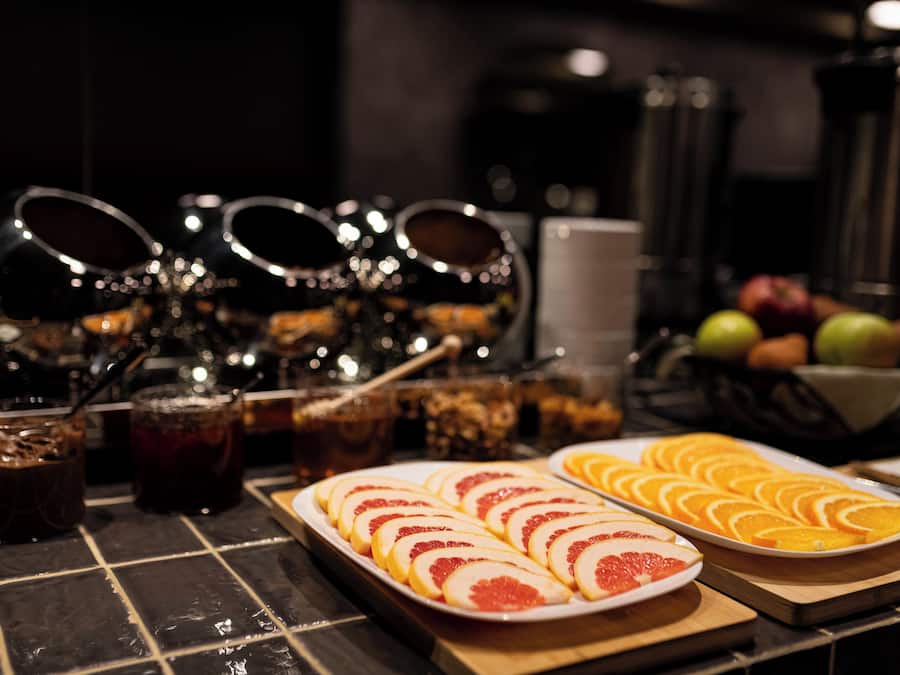 Une table de buffet avec des fruits coupés en tranches, des boissons et des condiments.