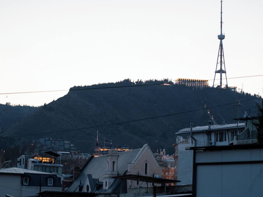 A cityscape with a prominent tower, buildings with flat roofs, and a hilly backdrop.