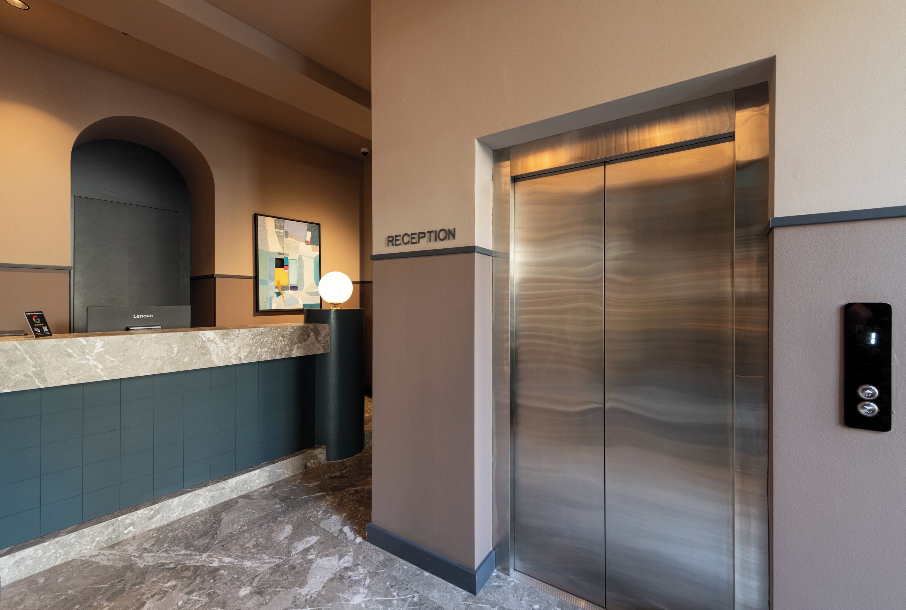 A reception area with a reception desk, a wall-mounted sign reading 'RECEPTION,' and a modern elevator.