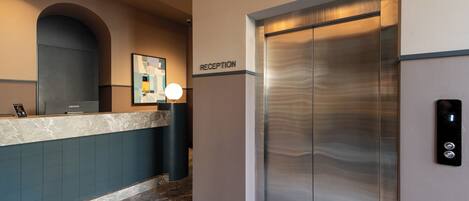 A reception area with a reception desk, a wall-mounted sign reading 'RECEPTION,' and a modern elevator.