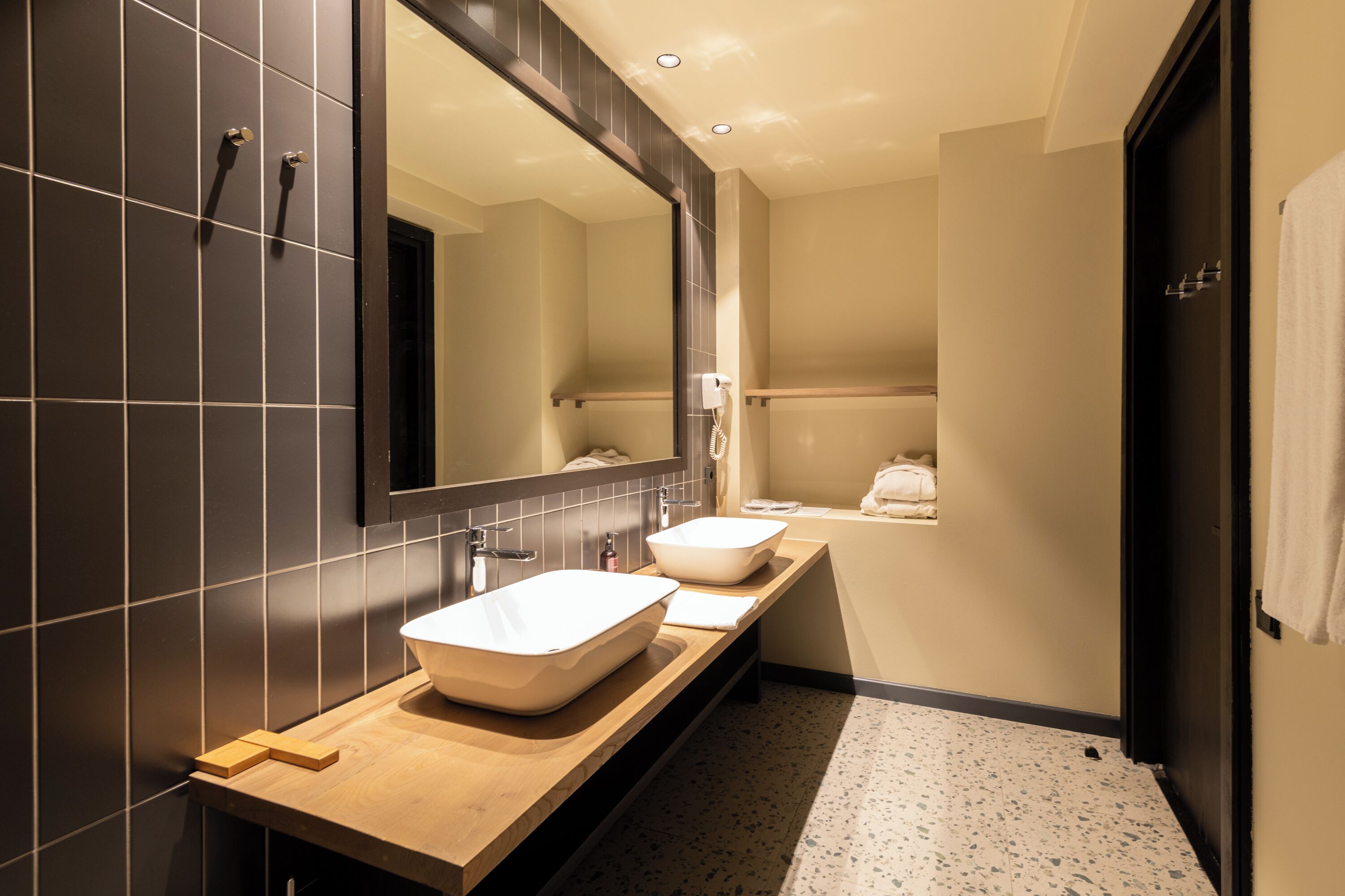 Een moderne badkamer met een grote spiegel, twee wastafels en een douchehoek.