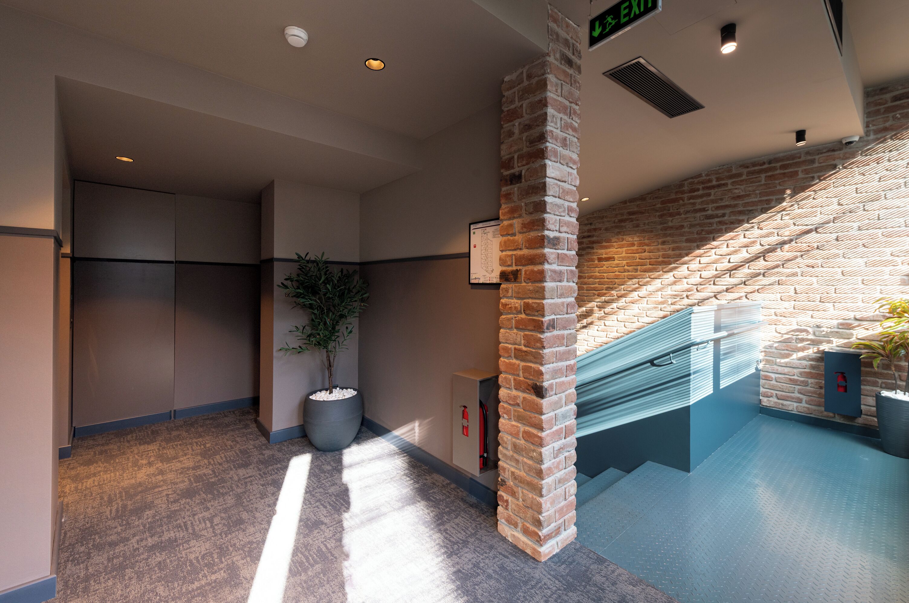 A modern interior with a brick column, a staircase, and a potted plant.