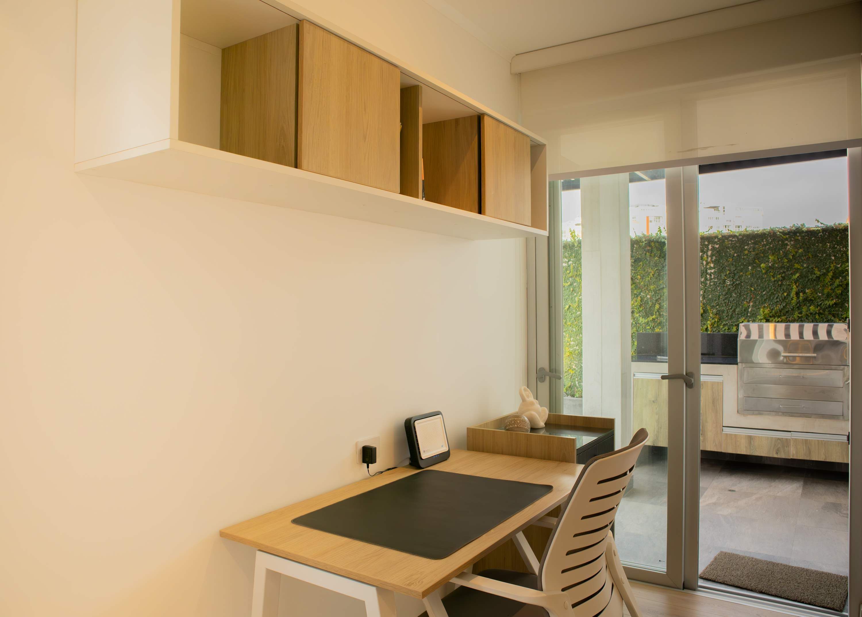 A modern kitchen with wooden cabinets, a dining table, and a view of a garden through glass doors.